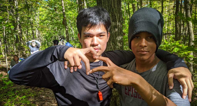 two teens make a heart using their hands while on a backpacking trip with outward bound